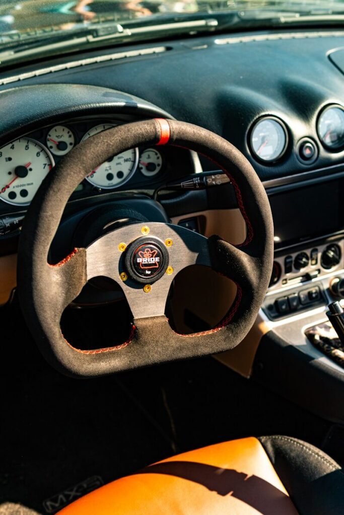 Suede steering wheel and dashboard of a classic car interior.